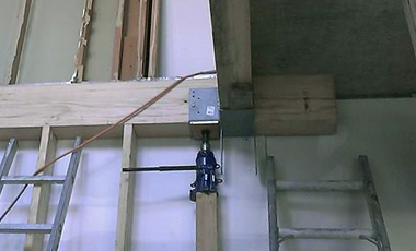Beams, connected together with steel saddles, are jacked up tight against the concrete slab.