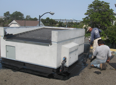 A crew works to apply hot asphalt around the elevator bulkhead.