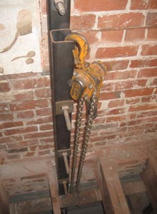 A chain hoist used to raise an angle iron into position at the bottom of the first floor ceiling joists.
