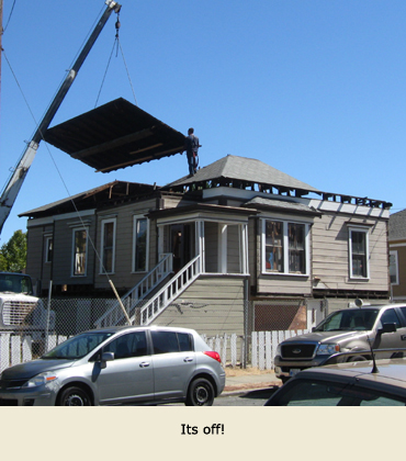 Moving a house in Martinez, California: A section of roof is lifted with a crane.