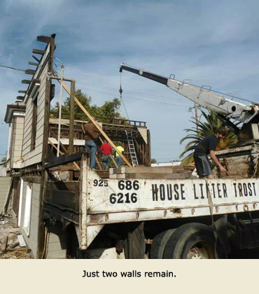 A Trost house movers truck waits while two walls remain for the house.