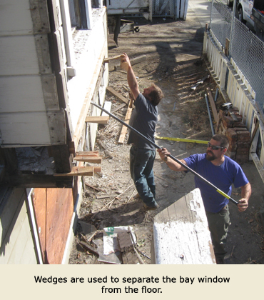 Matt Trost and Alberto Perez use wedges to separate a bay window as a part of moving the house.